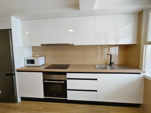 Cocina moderna con muebles blancos, encimera de madera, electrodomésticos integrados y frigorífico en piso de Carballo - Serdava