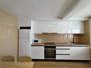 Cocina moderna con muebles blancos, electrodomésticos integrados y encimera de madera en piso de alquiler en Carballo - Serdava