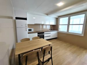 Cocina moderna con muebles blancos, mesa de madera y sillas en piso de alquiler en Carballo - Serdava