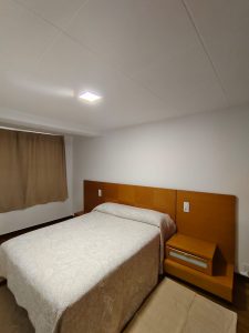 Dormitorio con cama de matrimonio y cabecero de madera en piso de alquiler en Carballo - Serdava