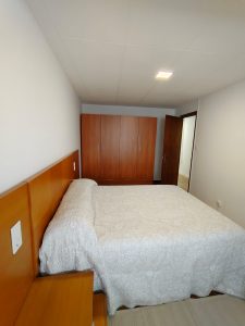 Dormitorio con cama de matrimonio, cabecero y armario de madera en piso de alquiler en Carballo - Serdava