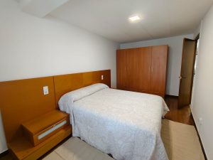 Dormitorio con cama de matrimonio, cabecero y armario de madera en piso de alquiler en Carballo - Serdava