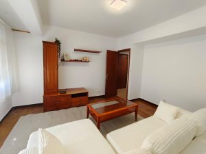 Salón luminoso con sofá blanco, mueble de madera y mesa de centro en piso de alquiler en Carballo - Serdava