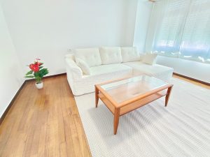Salón luminoso con sofá blanco, mesa de centro de madera y planta decorativa en piso de alquiler en Carballo - Serdava